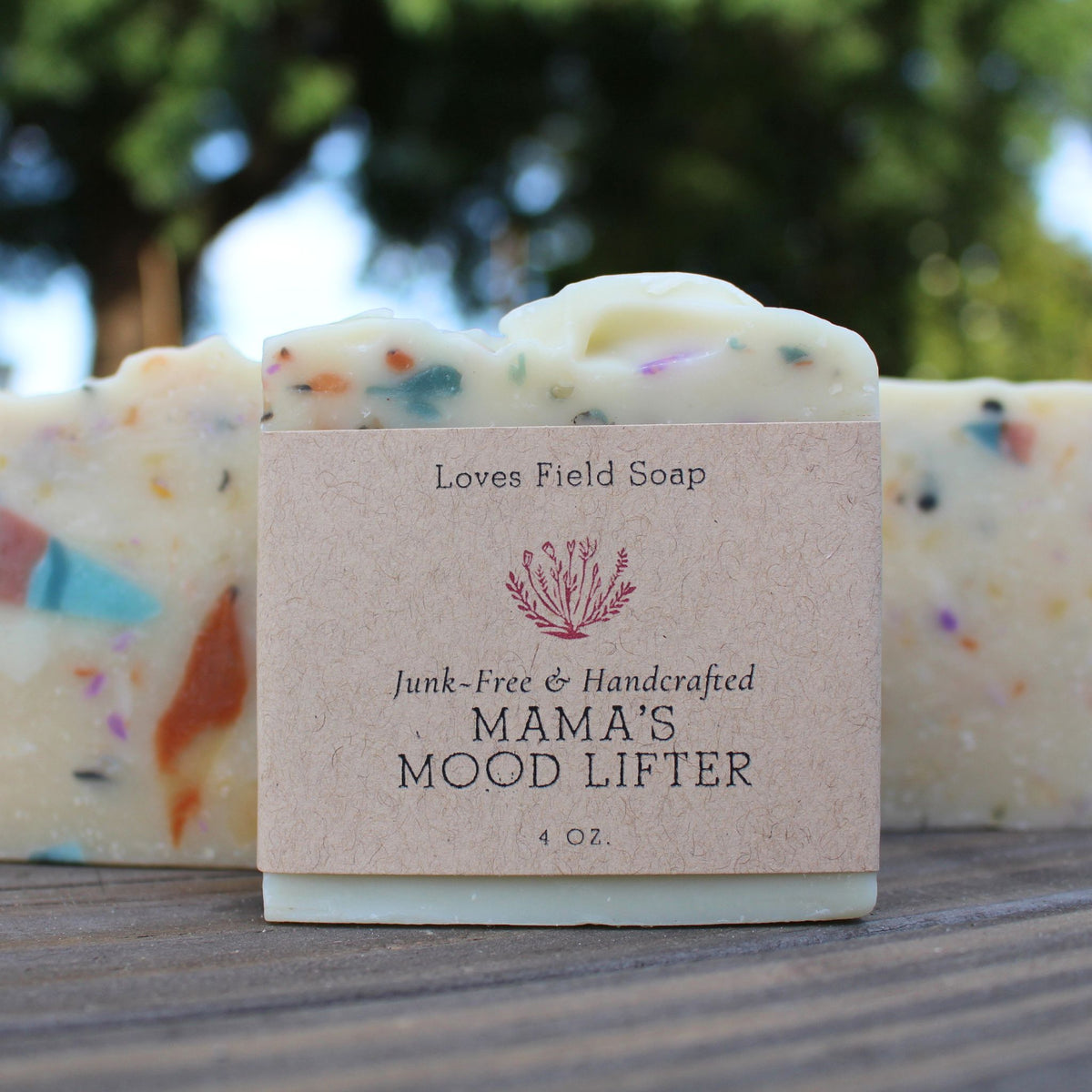 Bar of soap with a 'Mama's Mood Lifter' label on a wooden surface with a blurred natural background.