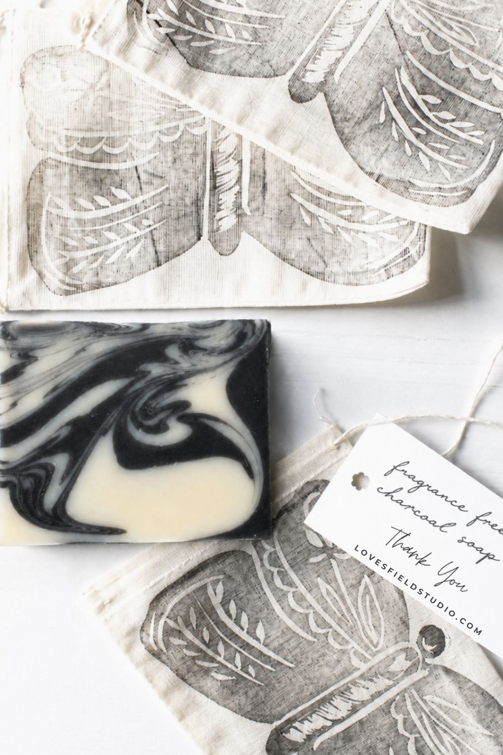 charcoal swirled bar of soap beside hand stamped butterfly drawstring bag