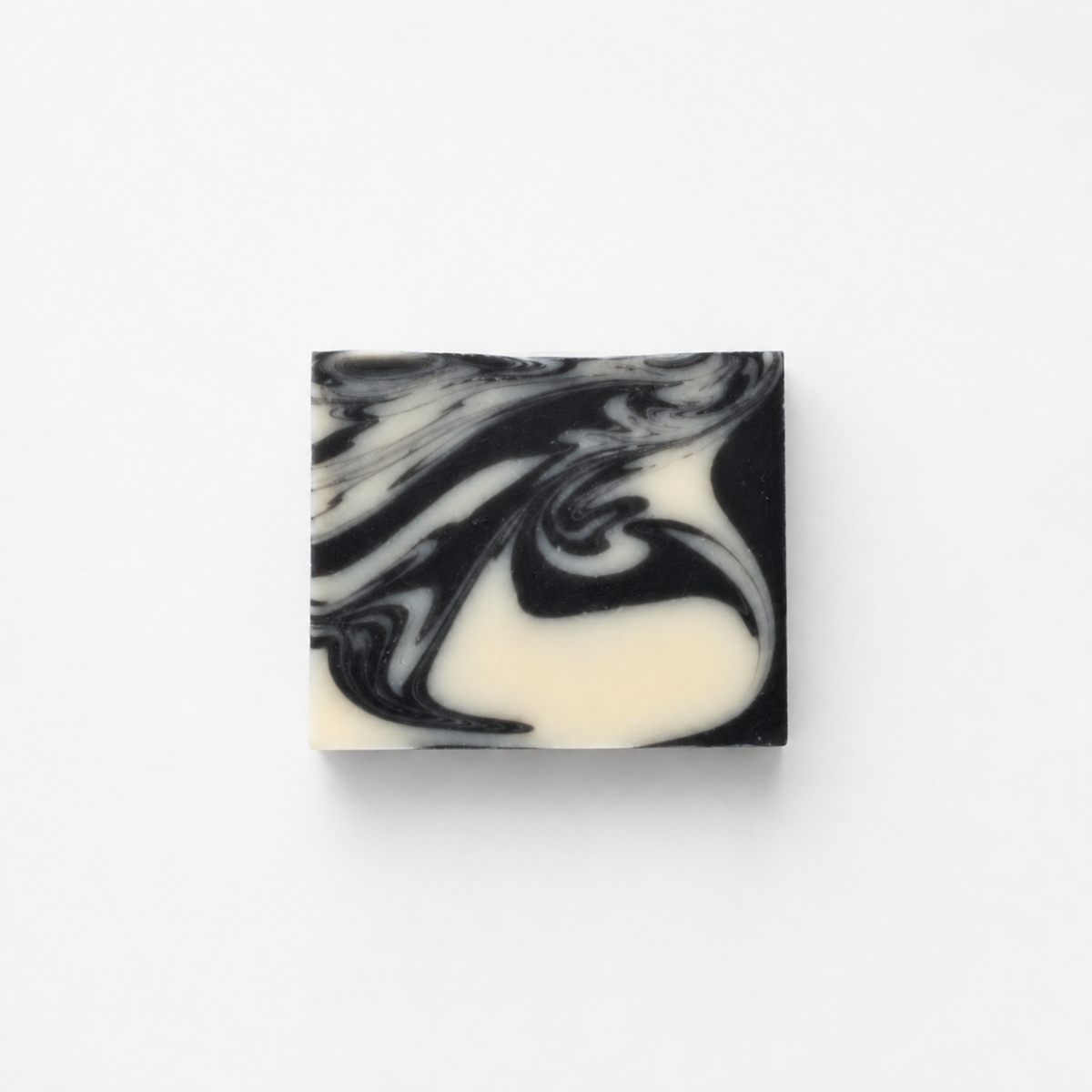 Fragrance-free charcoal and clay goat milk soap bar with black and white swirls on white background