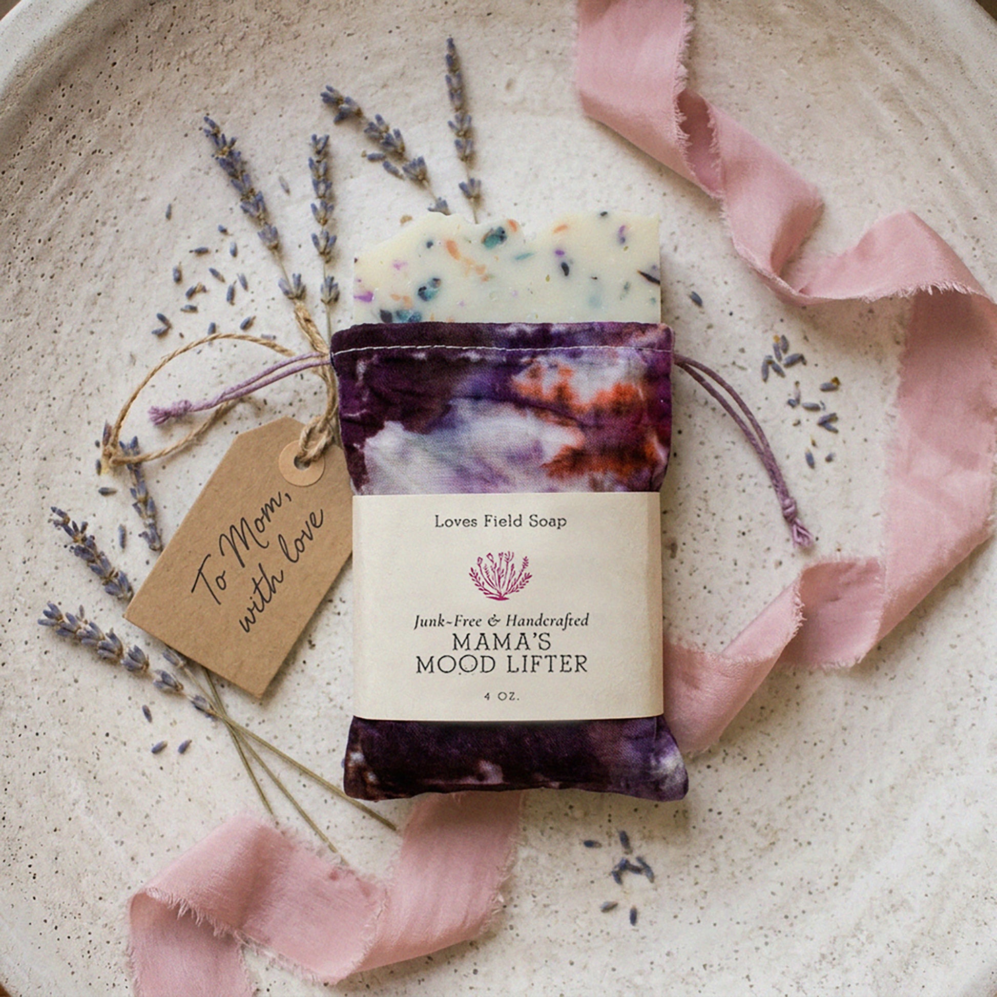 Bar of soap with a decorative ribbon and lavender on a textured surface