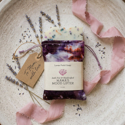 Bar of soap with a decorative ribbon and lavender on a textured surface